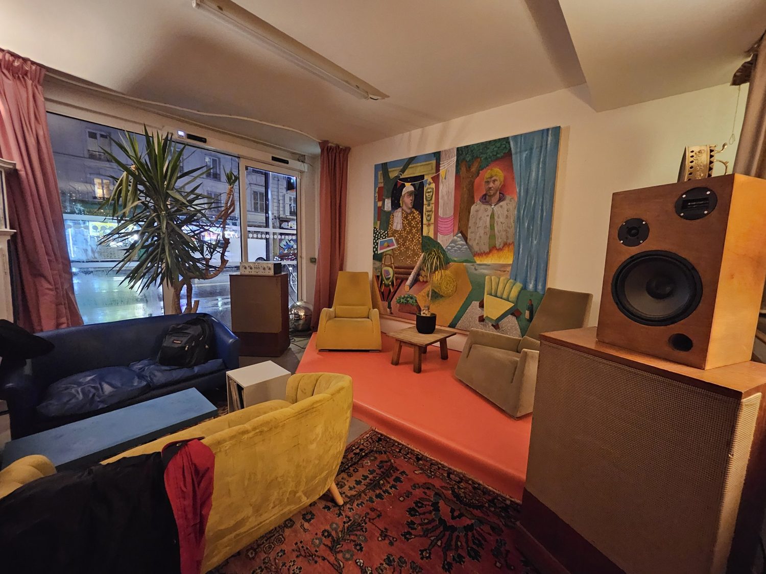 Le salon du bar avec son estrade corail, ses fauteuils moutarde et la grande peinture
